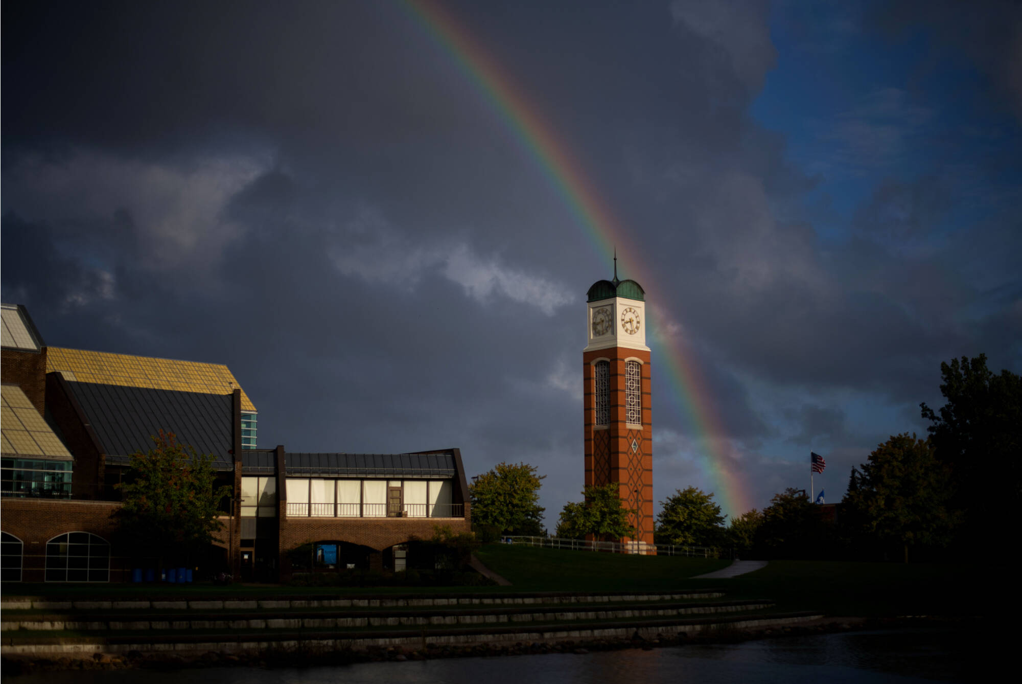 A storm darkened campus shot with a rainbow behind the clocktower